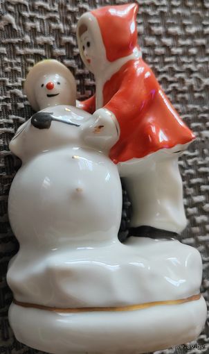 Девочка лепит снеговика.