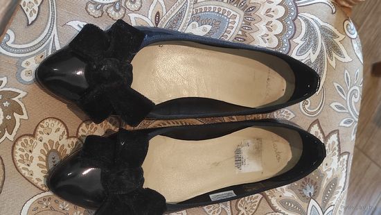 Красивые балетки Clarks на 37 размер. Очень мило смотрятся на ноги, с очаровательным бантом. Длина стельки примерно 24 см. Лак черного цвета, бант бархат. Не носила, маломерят, покупала без примерки и