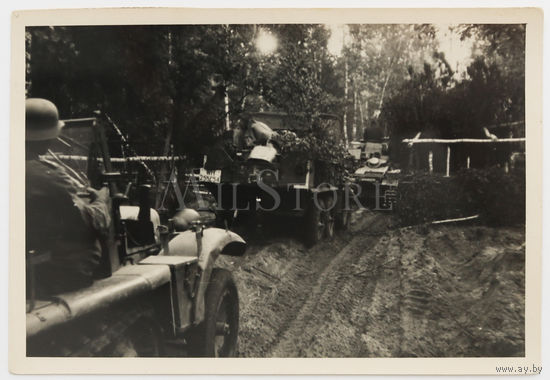 Немецкий солдат с трофейным советским ППШ в кабине тягача в составе колонны. Впереди едет легкий танк